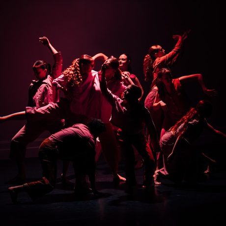 Group of dancers on stage bathed in red light AND WHITE LIGHT
