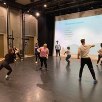 Dancers in motion on stage in a workshop setting