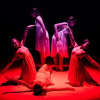 Five ballerinas in a red spotlight