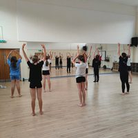 Children in a school dance studio performing to a mirror