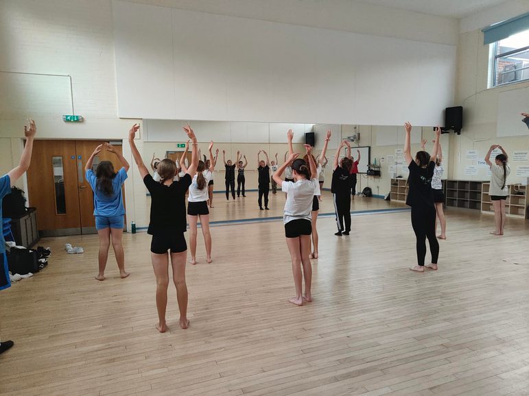 Children in a school dance studio performing to a mirror