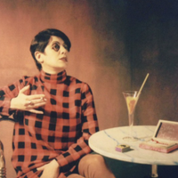 Lady with short dark hair sat at a table with drink