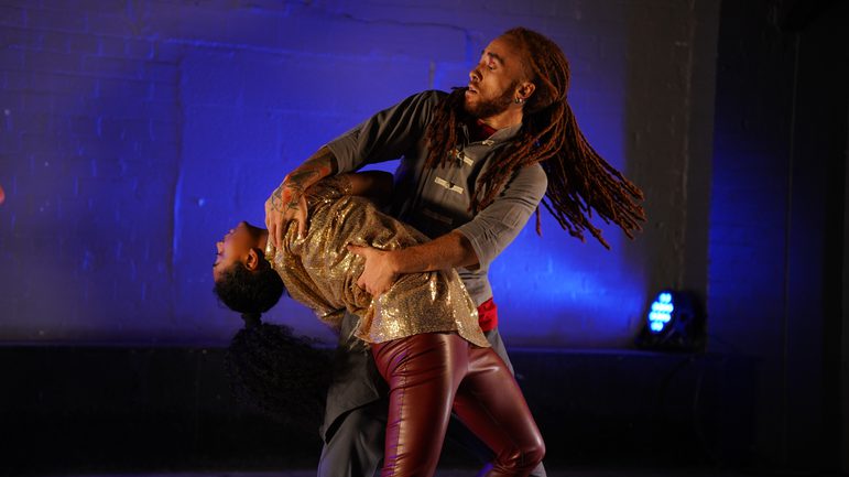 Two contemporary dancers in gold against a blue blackground