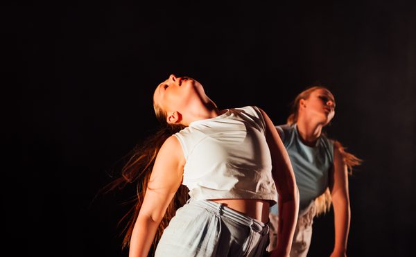 Two dancers in motion against a black background