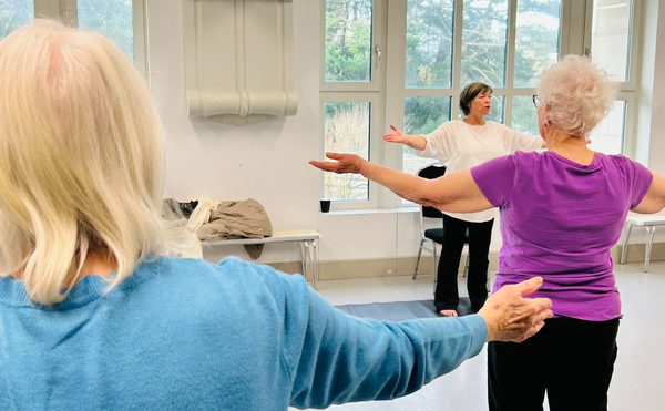 Two class participants, hands outstretched facing the teacher