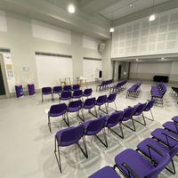 An empty dance studio with purple chairs laid out lecture style