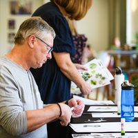 Person cutting paper whilst sat at a table doing arts and crafts