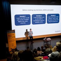 Person stood in front of large screen on stage