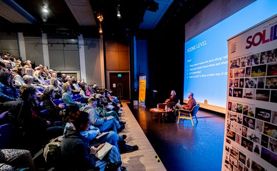Audience watching two speakers on a stage
