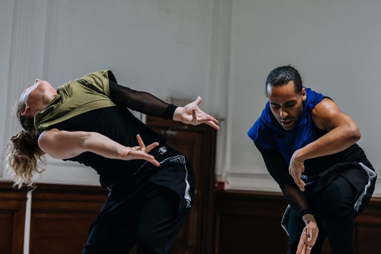 Two dancers in motion in a studio space