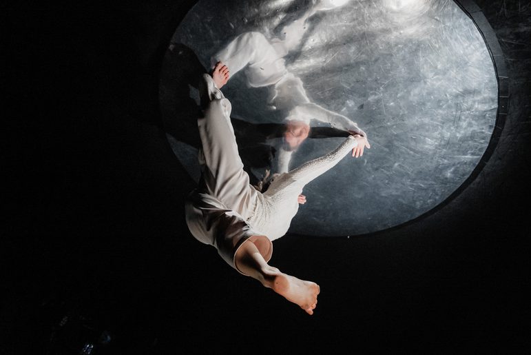 Ghostly dancers upside down on a moon like orb