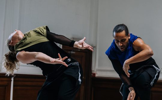 Two dancers in motion in a studio space