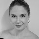 Woman with hair pulled back wearing off the shoulder dark top smiling