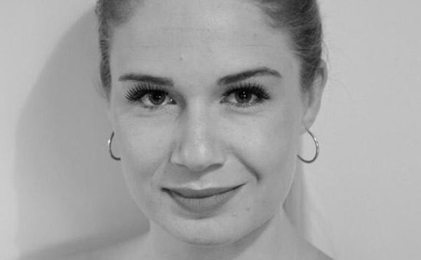 Woman with hair pulled back wearing off the shoulder dark top smiling